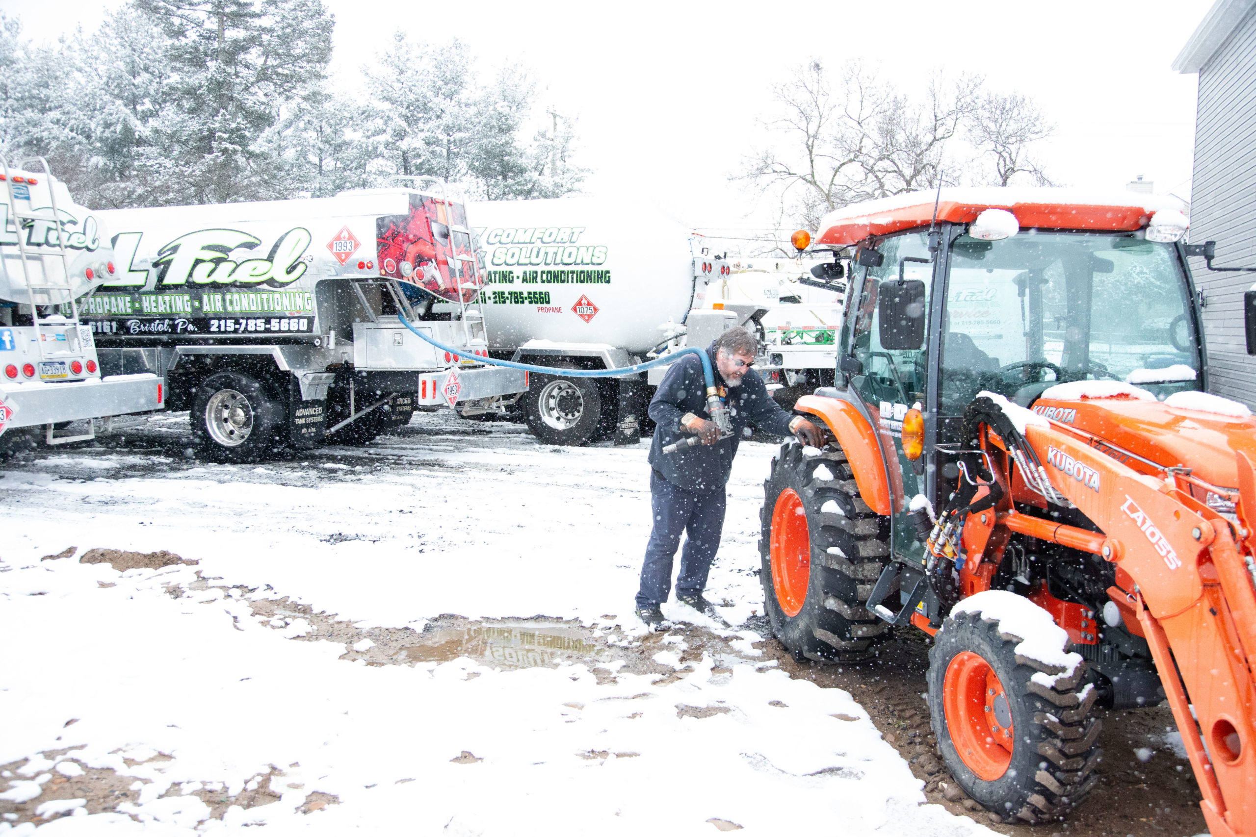 C&L team member fueling a tractor in front of C&L fuel trucks in the snow