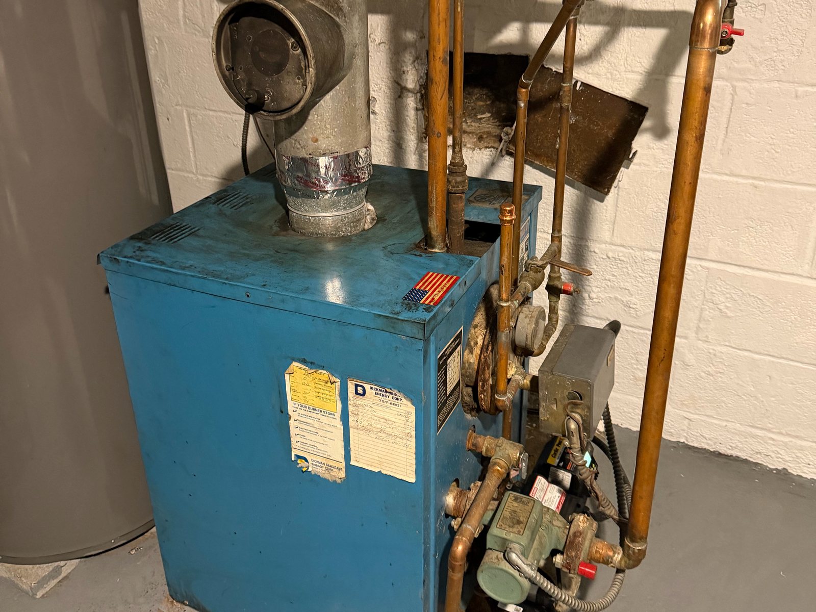 Blue boiler with its burner and controls in a basement