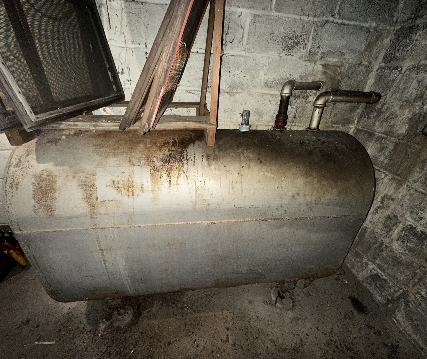 Older heating oil tank on legs in an unfinished basement