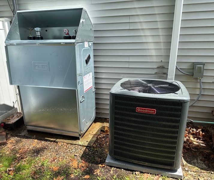 Outdoor heating oil tank with its lid open, beside a central air conditioner condenser