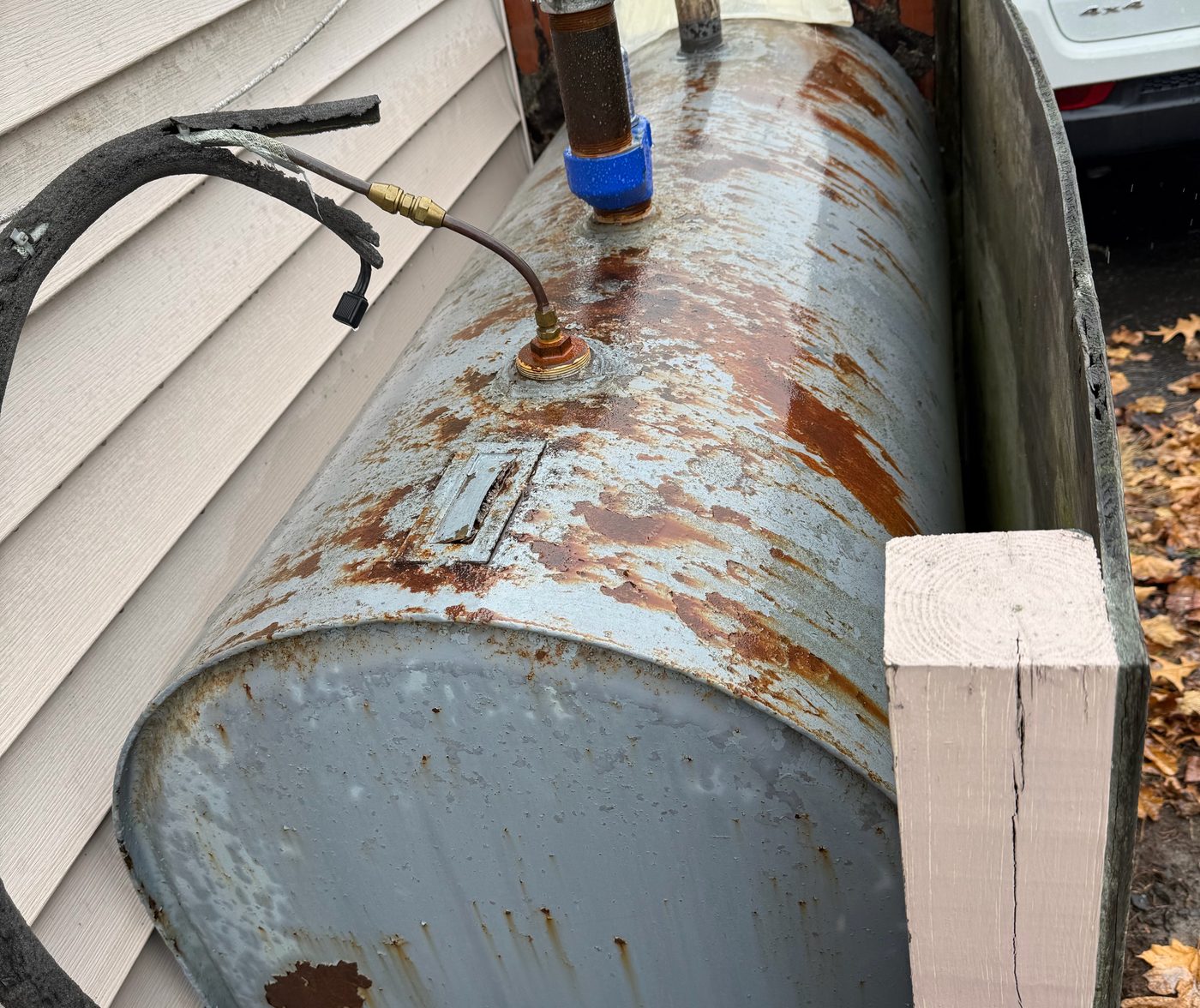 Old outdoor heating oil tank with heavy rust along its side