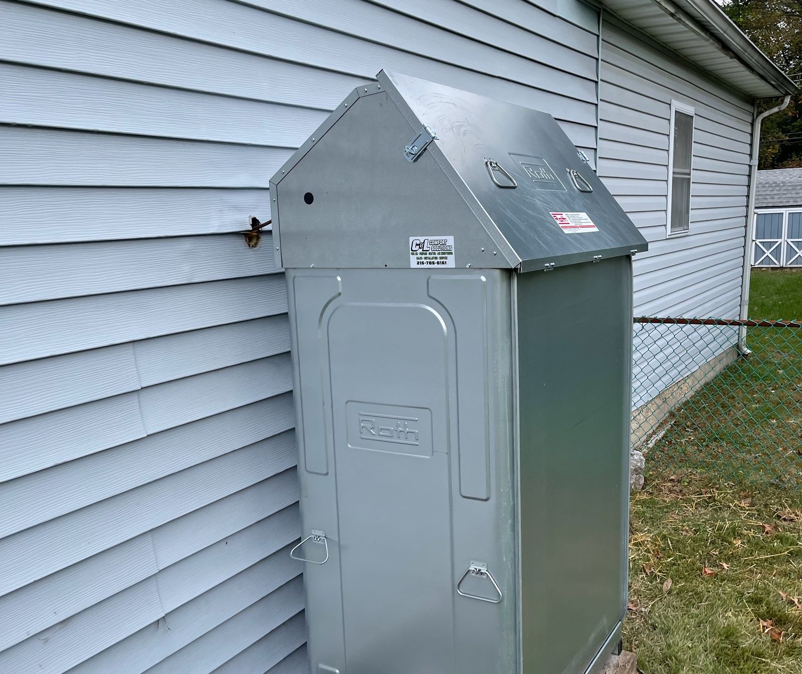 Roth double-wall outdoor heating oil tank beside a light blue house, with a C&L Fuel Inc. sticker on it