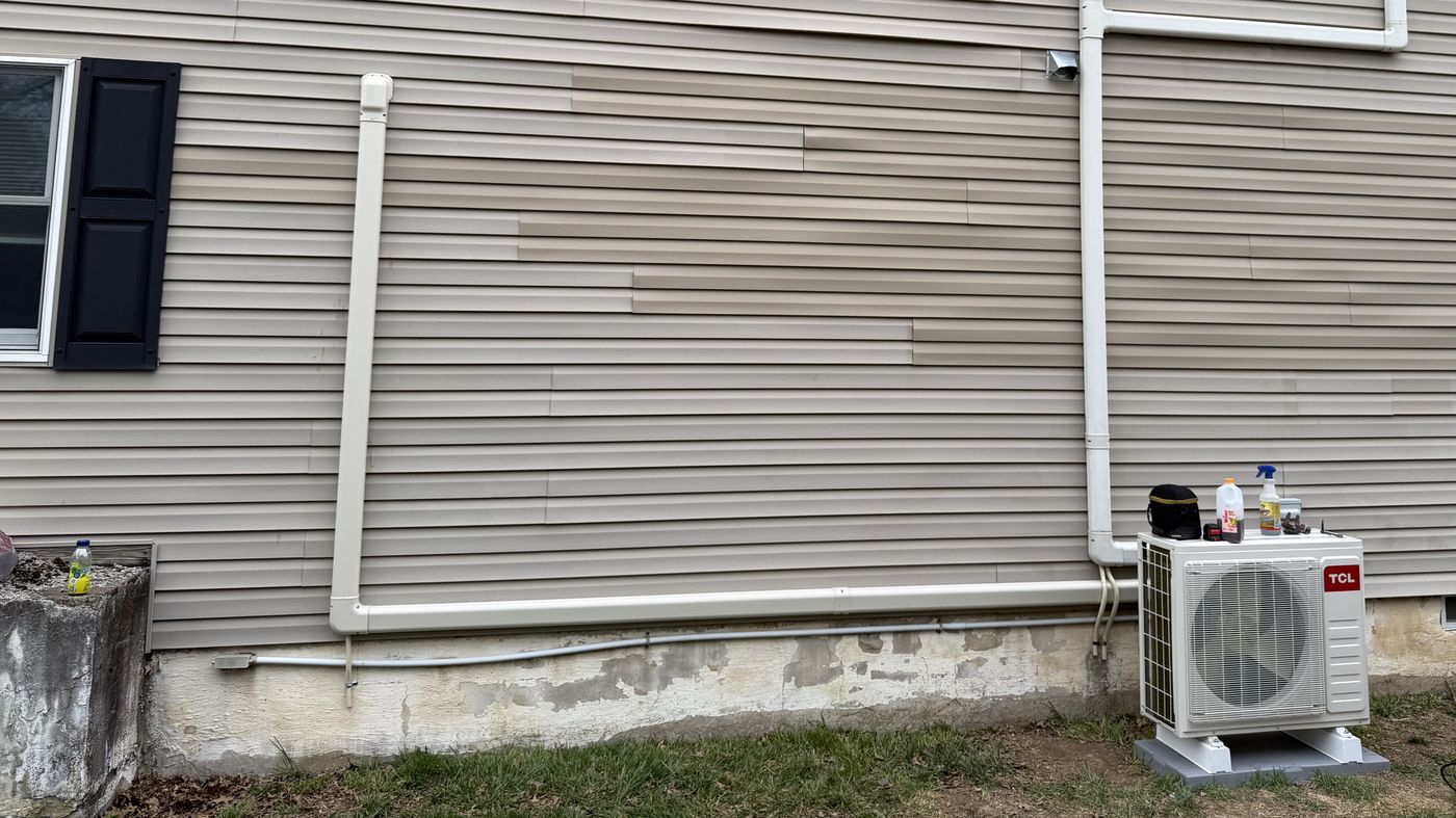 TCL ductless mini-split outdoor unit beside a tan-sided house, with covered line sets
