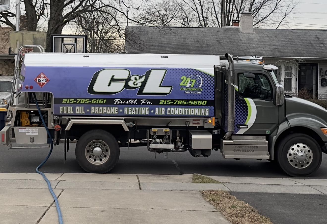 C&L Fuel heating oil delivery truck at the curb with its delivery hose run to the house