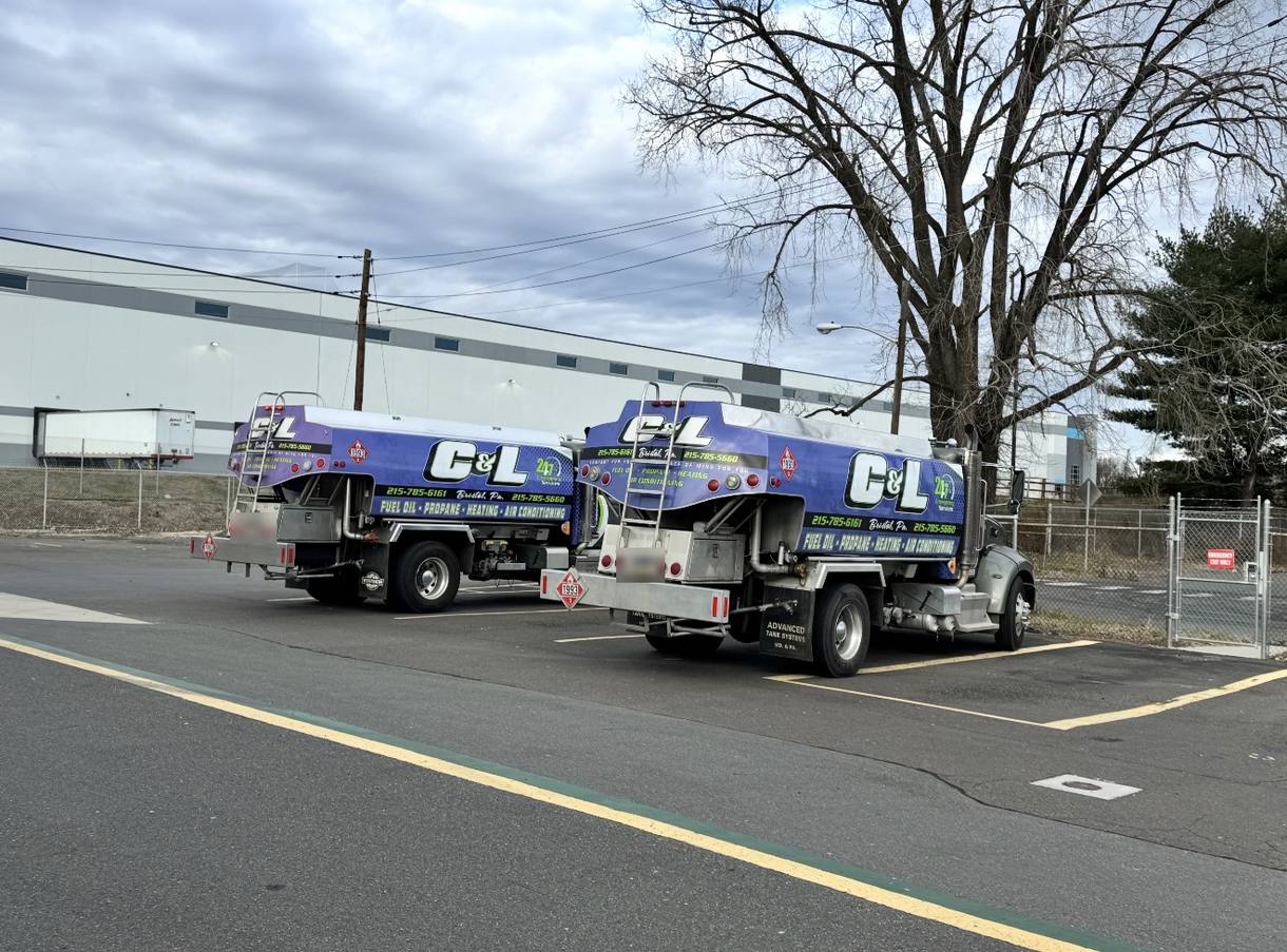 Two C&L Fuel heating oil delivery trucks parked in a lot, seen from the rear
