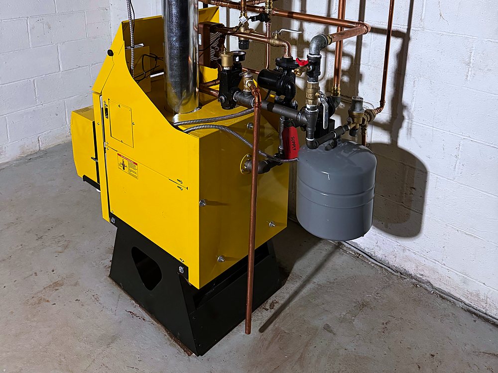 Yellow gas boiler with an expansion tank, zone valves and copper piping in a basement