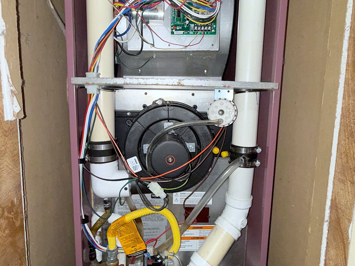 Older gas furnace in a closet with its panels off for service