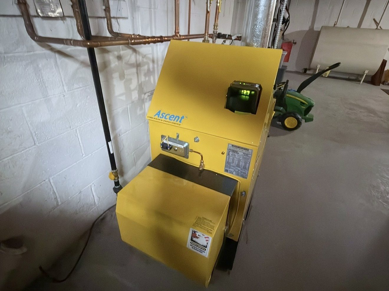 Yellow Energy Kinetics Ascent boiler with its Energy Manager display and copper gas piping in a basement