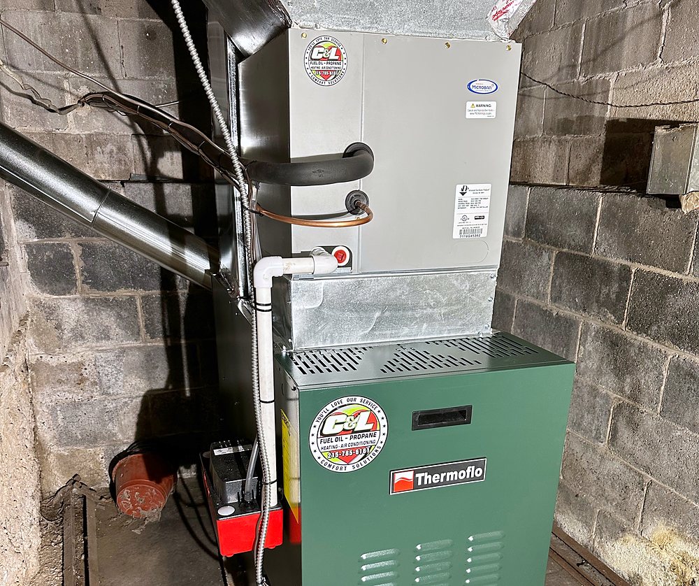 Indoor air conditioning coil cabinet with its refrigerant lines, condensate drain and pump, on top of a Thermoflo furnace with the C&L sticker