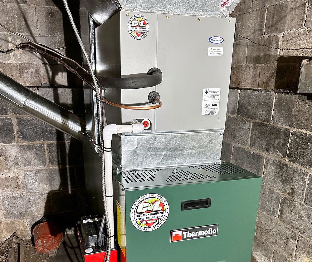 Indoor air conditioning coil cabinet with its refrigerant lines, condensate drain and pump, on top of a Thermoflo furnace with the C&L sticker