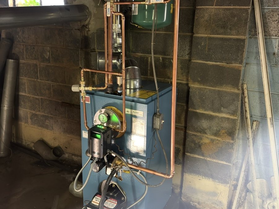 Blue boiler with copper piping against a block wall