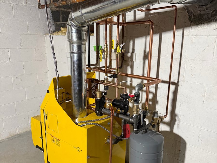 Yellow gas boiler with new copper piping, zone valves and an expansion tank in a basement