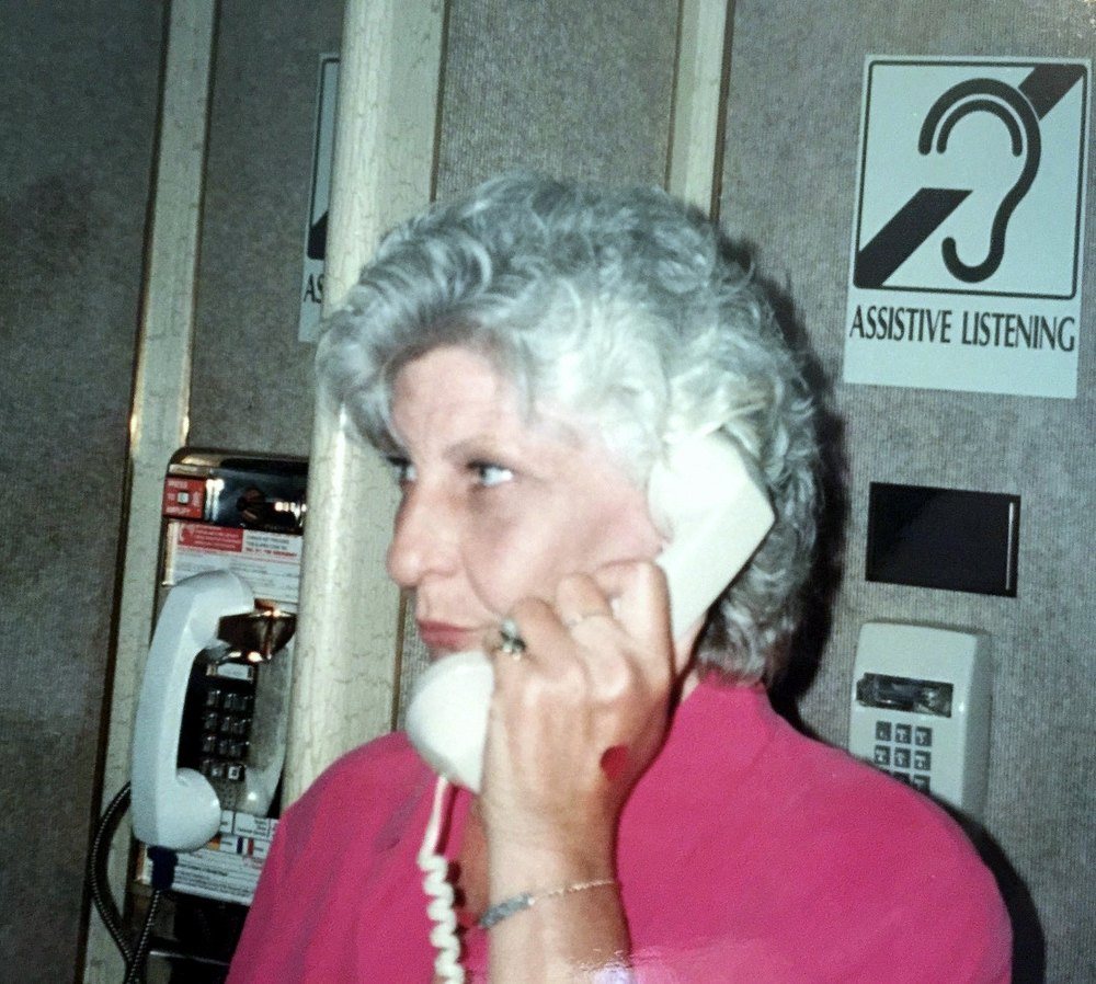 Susan talking on a corded phone beside a row of payphones