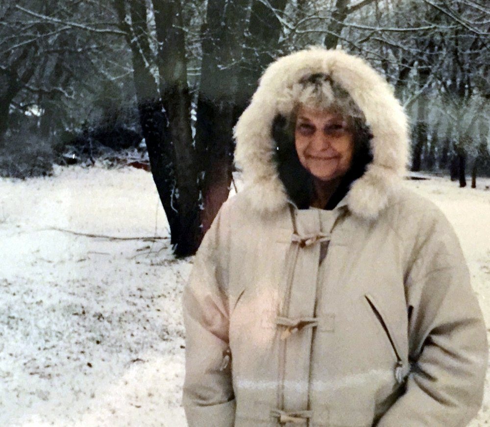 Susan in a white hooded winter coat standing in the snow