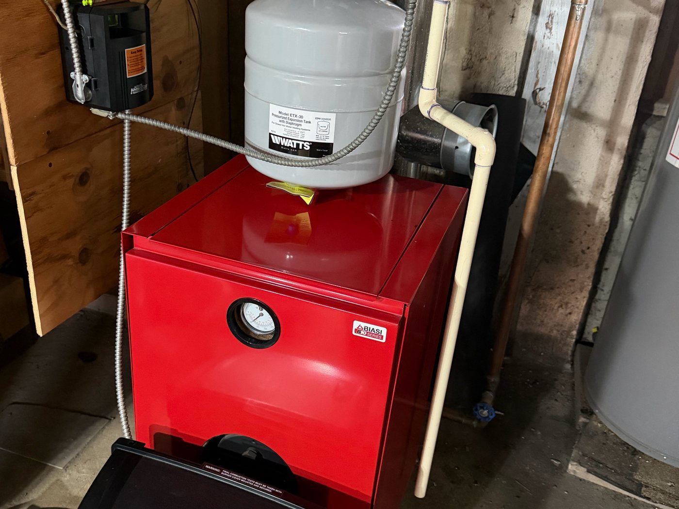 Red oil boiler with an expansion tank mounted on top in a basement