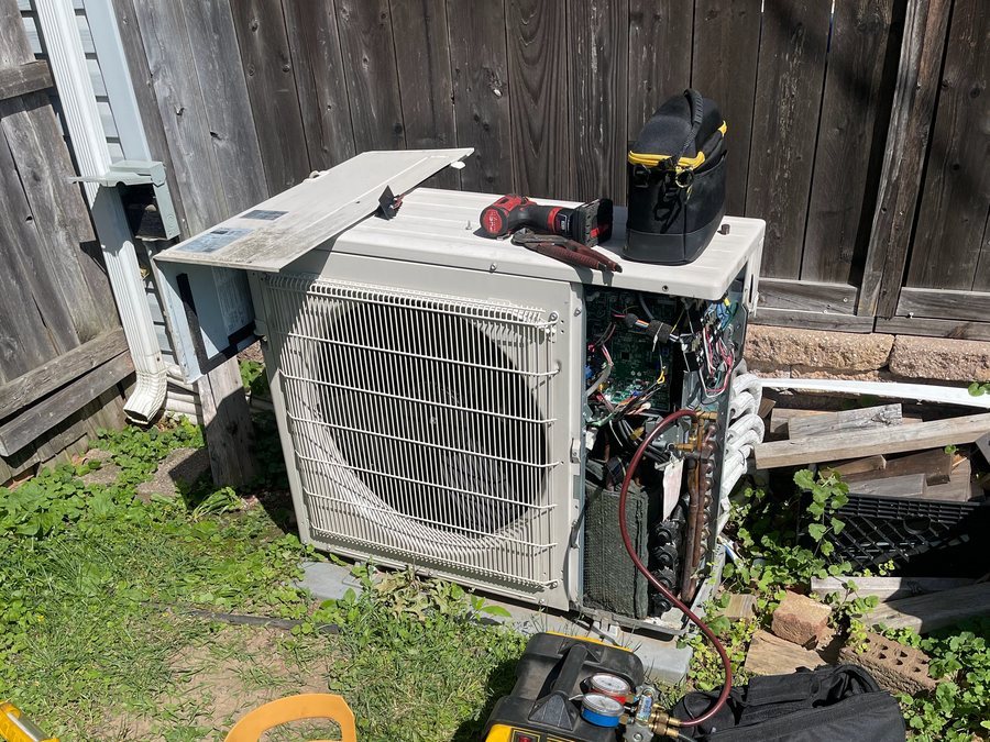 Ductless outdoor unit being repaired with gauges and a recovery machine
